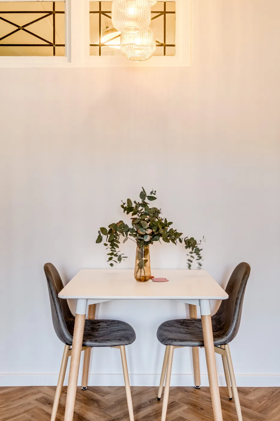 Esstisch für zwei am Fenster, mit Eukalyptus in der Vase